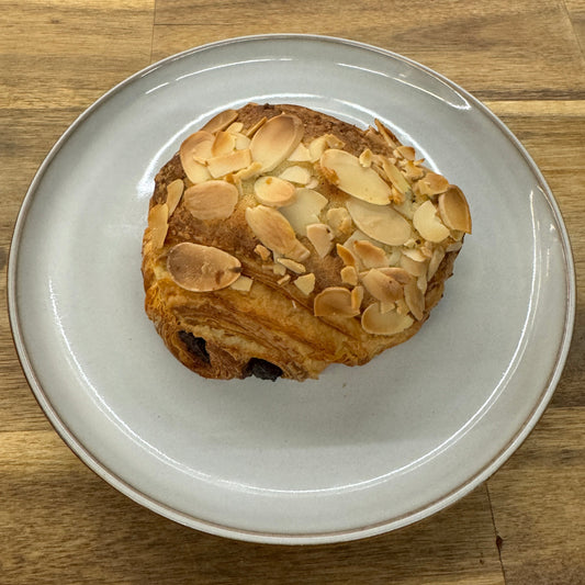 A luscious chocolate almond croissant, showcasing a rich cocoa-infused filling intertwined with layers of flaky pastry.