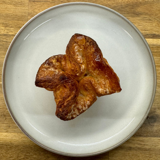 A mouthwatering kouign amann showcasing its golden-brown, caramelized exterior and intricate layers of flaky pastry.